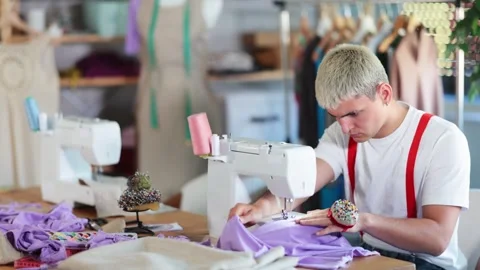 Focused young tailor sewing textile sitting at her workplace in tailor shop Video stock 329391683
