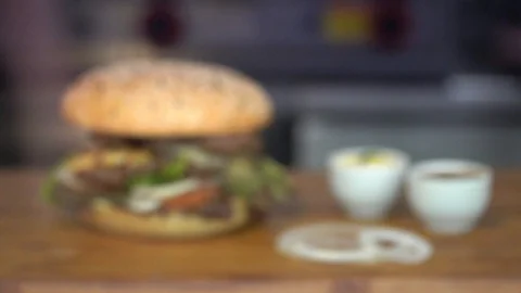 Focusing on a big burger with meat, tomatoes, egg, onion rings and salad on a Stock Footage 120261396