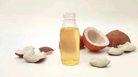 Focusing coconut oil plastic bottle with split coconuts in background Stock Footage 275670422