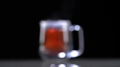 Focusing in a glass mug with red fruit tea evaporates on a black background Video stock 144431246