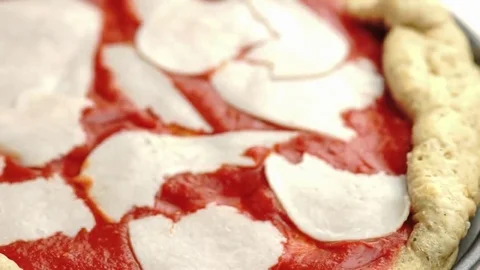 Focusing in on home made thick crust pizza that is being prepared with sliced Stock Footage 69184512