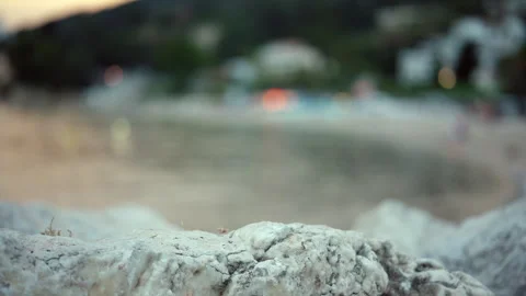 Focusing on rock texture with a blurred beach, sea, and city lights creating Stock Footage 339809424