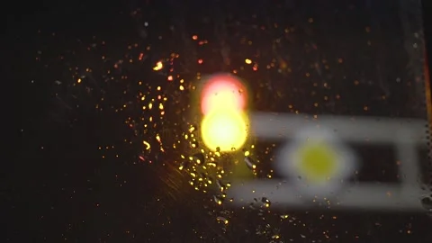 Focusing on traffic light through the windshield with raindrops on it Stock Footage 147007917