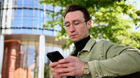 Focusing white man using digital smartphone sit on parapet outside, young Cau Video stock 207041601