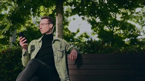 Focusing white man using digital smartphone sit on parapet outside, young Cau Vidéo 207041729