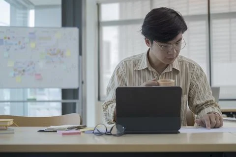 Focussed young businessman using computer tablet and checking financial repor 写真素材