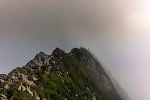 Fog and clouds enveloping a clmber on the steep ridge of the majestic Schaefl Stock Photos