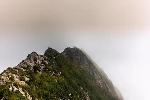 Fog and clouds enveloping a clmber on the steep ridge of the majestic Schaefl Stock Photos