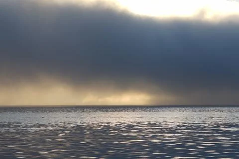 Fog and clouds hovering over the water. Stock Photos