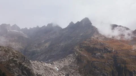 Fog and clouds moving over rocky mountain peaks at Furka Pass Switzerland Stock Footage 320458328