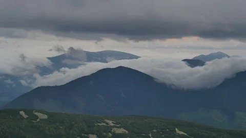 Fog and clouds rolling over green mountain hills Vídeos de archivo 77605176