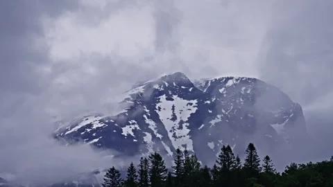 Fog and clouds surrounds a mountain on a gray day Stock Footage 267684344