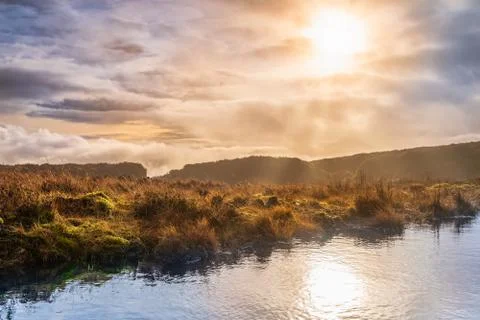 Fog and dramatic sky over a swamp with sun reflecting in a lake Stock Photos