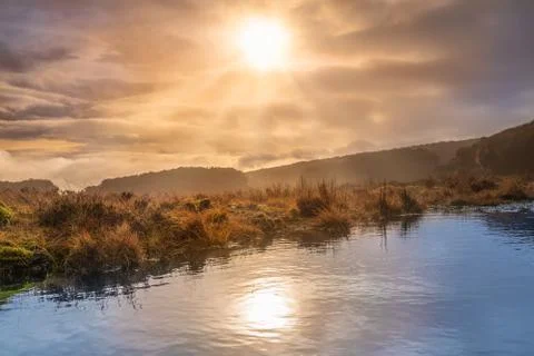Fog and dramatic sky over a swamp with sun reflecting in a lake Stock Photos