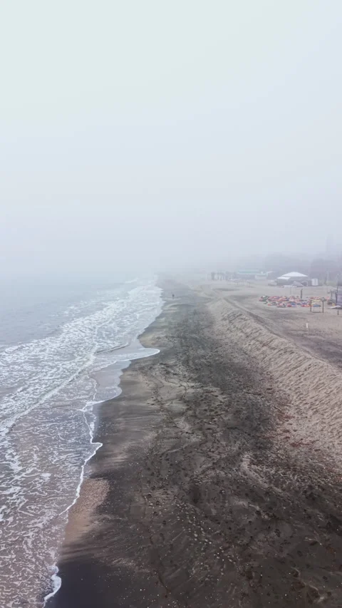Fog covers the beach as waves gently touch the shore in early morning hours by Stock Footage 337903070