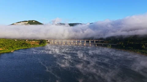 Fog covers a river and a bridge while mountains stand tall in the background Stock Footage 340767205