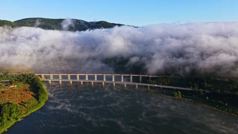 Fog covers a river valley as a bridge stands tall against the misty backdrop of Stock Footage 340765411