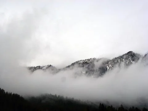 Fog is creeping over the mountain range. A picturesque panorama of wild nature Stock Photos