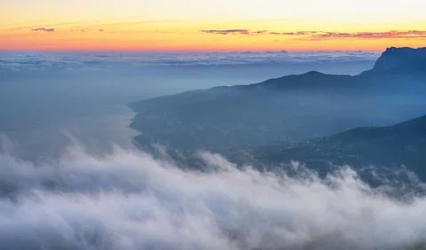 Fog drapes over the valley, creating a serene panorama of the mountain landscape Stock Photos