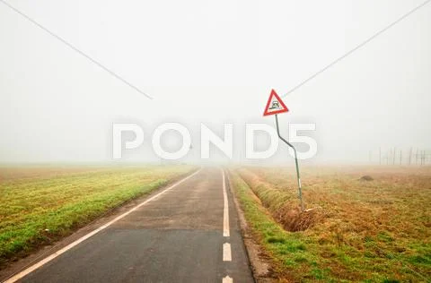 Fog on empty rural road with danger sign Stock Photos