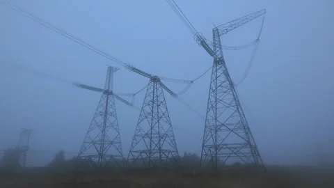 Fog envelops power lines as dawn breaks over an industrial landscape in the Stock Footage 288194790