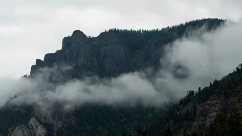 Fog moving in front of a mountain cliff Stock Footage 154899444