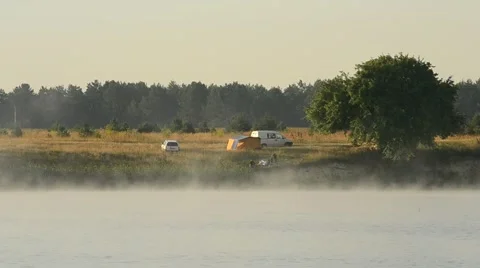 Fog over a lake or river with tourist tents and people on shore Stock Footage 55763870