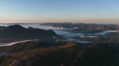 Fog rolling over mountains and lakes in early morning light, norway Video stock 317102384