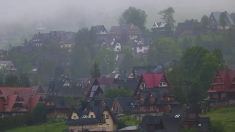 Fog rolling through a mountain forest with few visible village houses. Fogg.. Vídeos de archivo 329063696