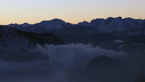 Fog sits gently between dark mountain ridges Stock Footage 102214714