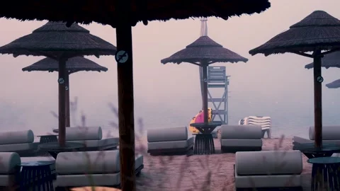 Fog slowly covering empty beach with umbrellas and lounge chairs Video stock 288242586