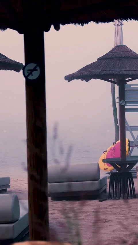 Fog slowly covering empty beach with umbrellas and lounge chairs Stock Footage 288242800