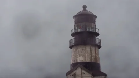 Fog surrounding an old lighthouse on the coast Video stock 125119134
