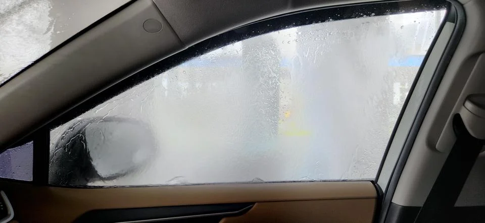 Fogged side window with water streams inside automatic car wash, interior vie Stock Photos