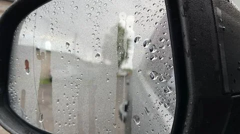 Fogged wet side mirror of the car, raindrops on the glass, close-up Stock Photos