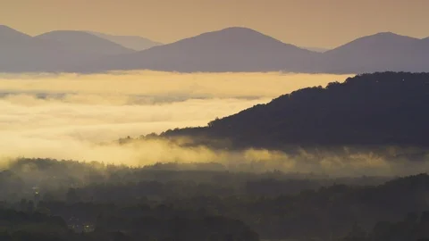 Foggy clouds amidst the mountain ranges at sunrise Stock Footage 103824330