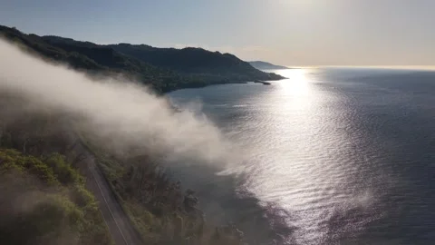 Foggy Coastal Road at Sunset | Drone Pullback Over Blue Sea 4K 60fps Stock Footage 337191953