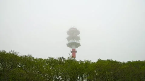 Foggy day red and white lighthouse rising above green trees in overcast weath Stock Footage 335288735
