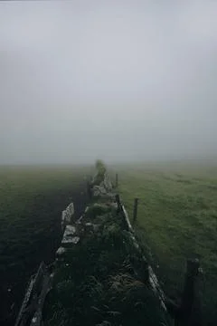 Foggy Grass Fields Divided by Stone Wall Stock Photos