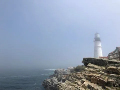 Foggy lighthouse overlooking cliffs Stock Photos