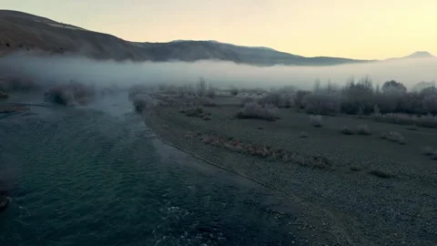 A foggy mountain range with a river running through it Stock Footage 327962078