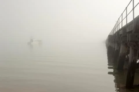 Foggy ocean or lake at pier with boats background Stock Photos