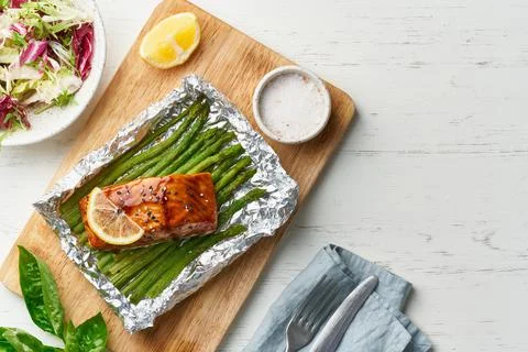 Foil pack dinner with red fish. Fillet of salmon with asparagus. Oven-baked hot Stock Photos