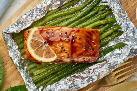 Foil pack dinner with red fish. Fillet of salmon with asparagus. Oven-baked hot Stock Photos