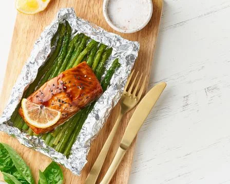 Foil pack dinner with red fish. Fillet of salmon with asparagus. Oven-baked hot Stock Photos