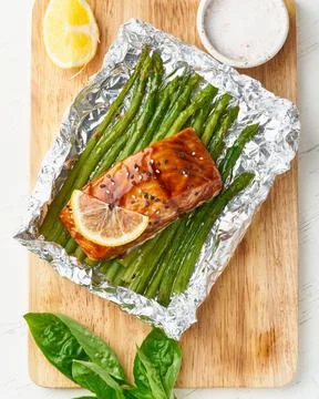Foil pack dinner with red fish. Fillet of salmon with asparagus. Oven-baked hot Stock Photos