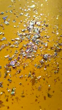 Foil pieces on yellow background with multi-colored shine. Abstract fashion Stock Photos