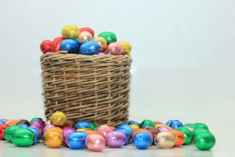 Foil wrapped chocolate easter eggs in a wicker basket Stock Photos