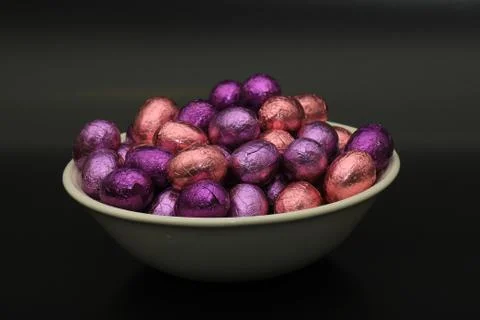 Foil wrapped chocolate easter eggs in a white porcelain bowl Stock Photos