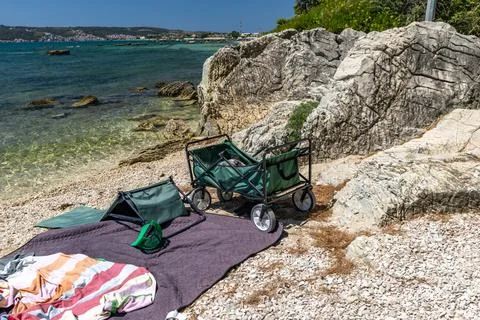A foldable transport trolley placed on a blanket by the seashore, own food .. Stock Photos
